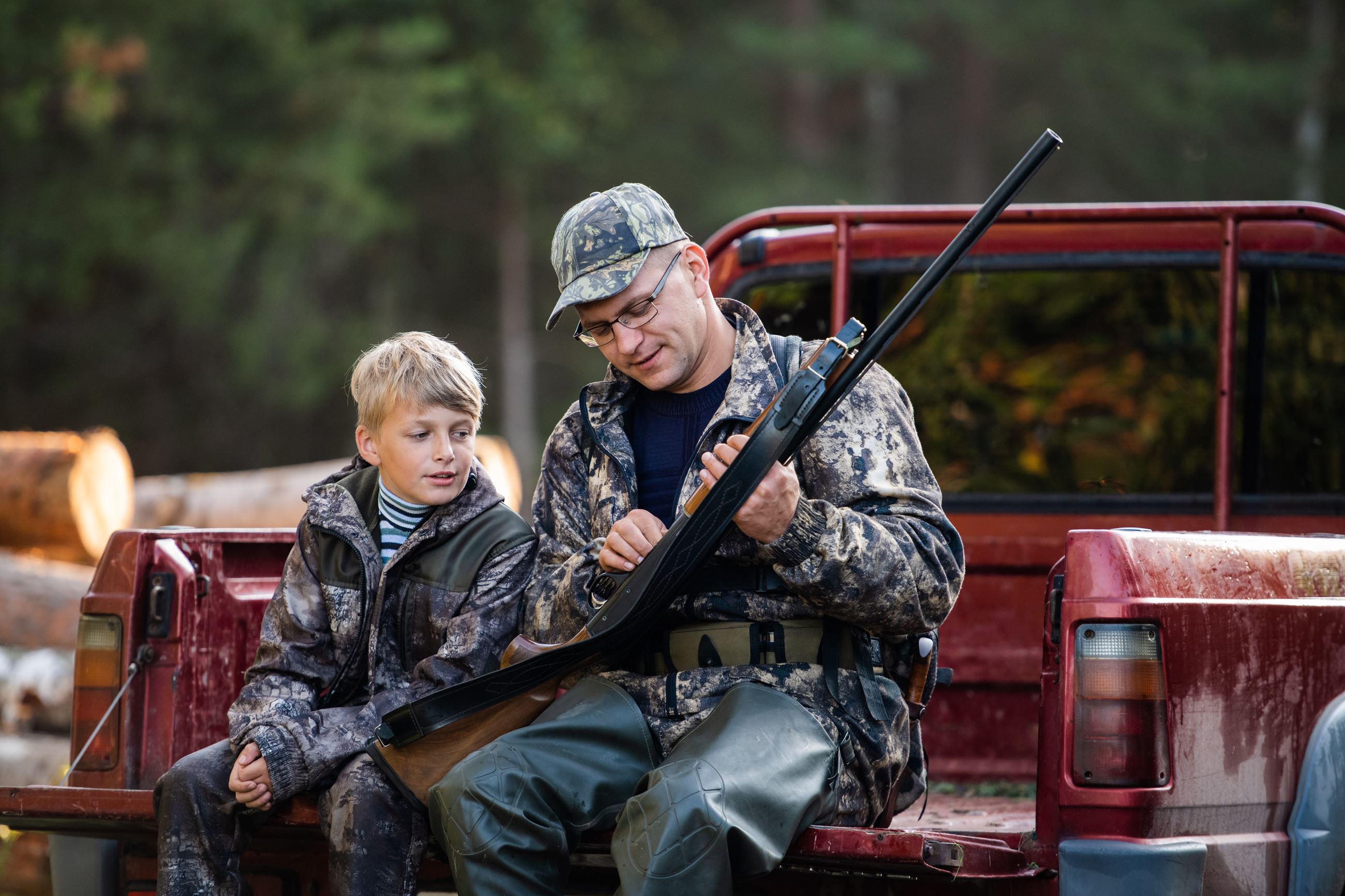 father and son sitting on truck with gun