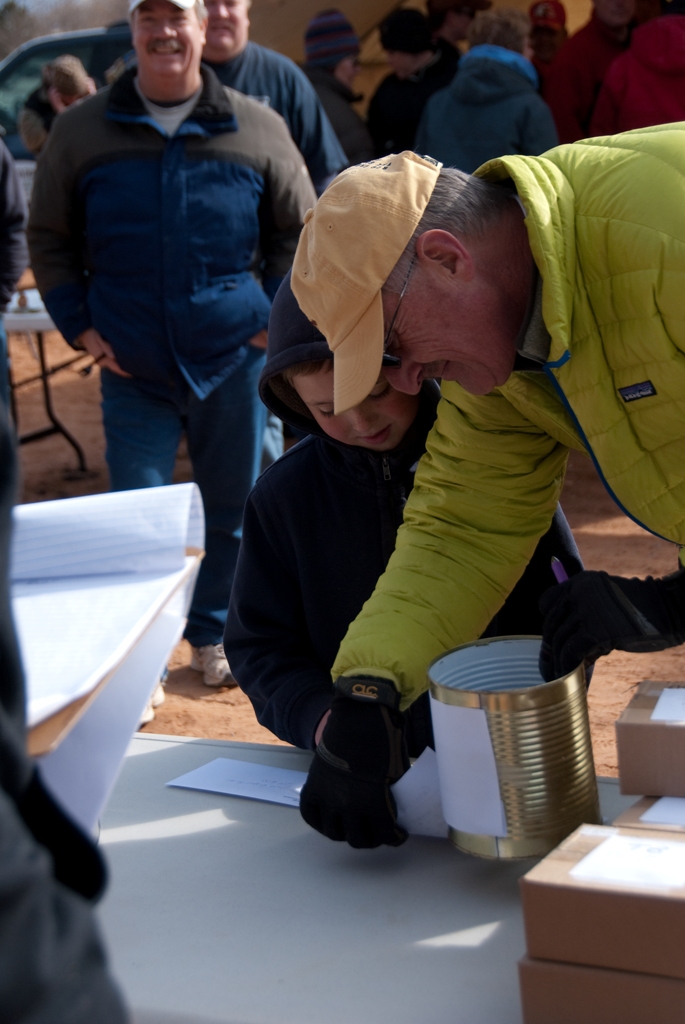 Photo of Participant drawing a ticket from the can for someone else to win a prize during the 2012 Burbot Bash