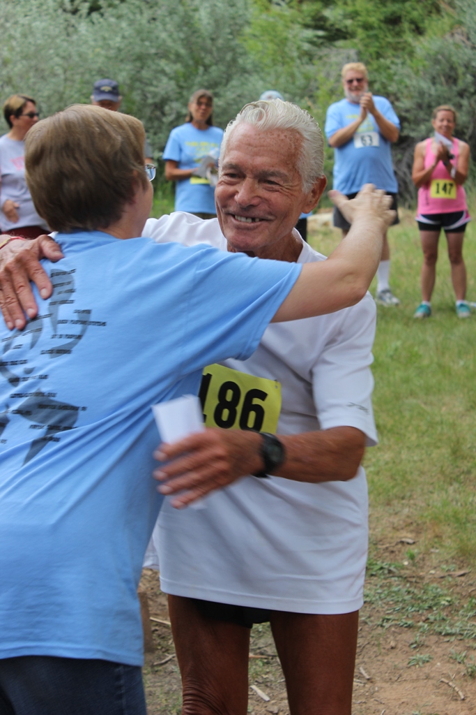 Photo of Currie Harlacher (age 86) and Race Director Sue Morgan hug after the awards 