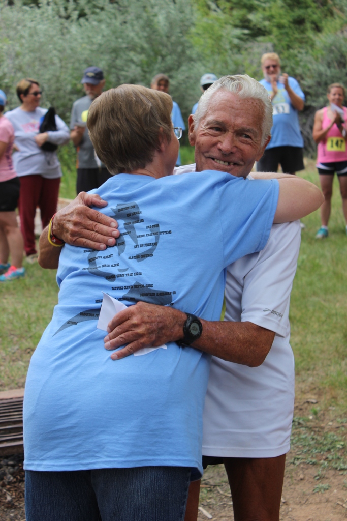 Photo of Currie Harlacher (age 86) and Race Director Sue Morgan hug after the awards 