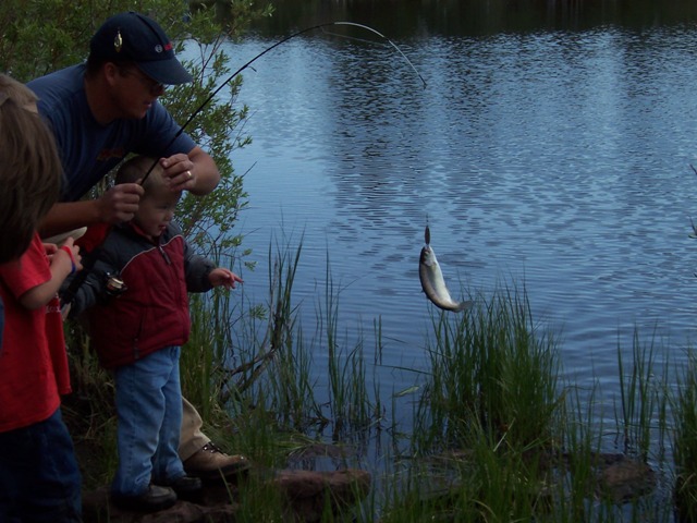 Photo of a fish dangling from the line as its be landed during the 2006 Kid's Fishing Derby at the Moose Ponds.